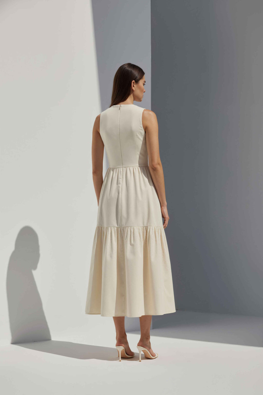 Anasua The Forme Edit Poplin Cotton Midi Dress in Halo Cream, a structured sleeveless cotton midi dress with a tiered skirt, photographed under natural sunlight.